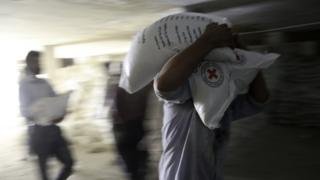 People unload supplies from a Syrian Arab Red Crescent (SARC) truck in the rebel-held town of Douma