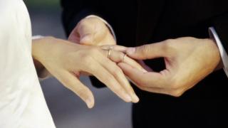 A groom putting a ring on the bride's finger