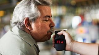 Hombre haciendo una prueba de alcohol con un alcoholímetro.