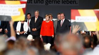German Chancellor Angela Merkel (C) and other party members sing the national anthem after addressing an election campaign rally of the Christian Democratic Union (CDU) in Bitterfeld, eastern Germany