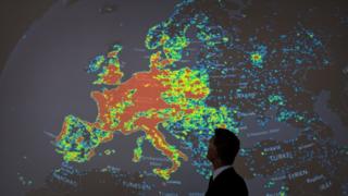 Человек стоит у карты с изображением сети зараженных компьютеров