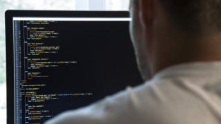 A coder looks at a computer