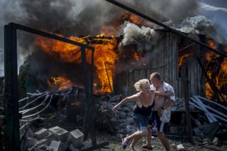 A couple escape a fire at a house destroyed by an air attack in the Luhanskaya village, Ukraine.