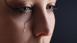 سيدة تبكي وتسيل دمعة على خدها