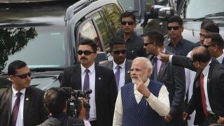 Indian Prime Minister Narendra Modi (C) holds up his inked finger after casting his vote in Ahmedabad on December 14, 2017.