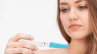 woman holding pregnancy test with negative result