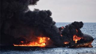 It shows smoke and flames coming from the burning oil tanker "Sanchi" at sea off the coast of eastern China
