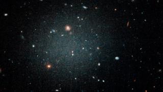 Una burbuja borrosa con otras galaxias que pueden verse a través de ella.
