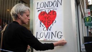 Woman pinning love London poster to post