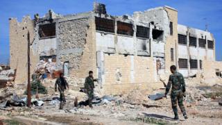 Syrian government troops walk inside the Kweiras air base, east of Aleppo, Syria