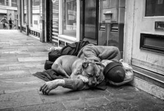 A homeless man sleeps with his dog in Birmingham City Centre.