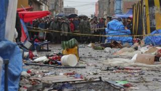 Locals watch from behind of a barricade at the scene of an explosion a day before, that caused six dead and 28 injured in a street market that remains cordoned off while the investigation continues in the city of Oruro, Bolivia,