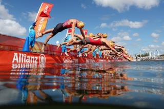 Athletes dive into water at the start of the women's triathlon