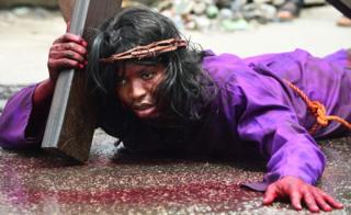 A man lies on the ground carrying a crucifix during a dramatisation of the crucifixion of Jesus Christ to mark Good Friday, heralding the start of Easter celebrations, in Lagos on March 30, 2018.