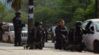 Policemen take cover behind a vehicle during a police operation to regain control of a prison, in Ciudad Victoria, in Tamaulipas state, Mexico, 6 June, 2017.