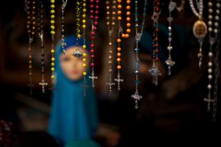 Rosary beads are displayed for selling next to a mannequin wearing a headscarf in a market stall at The Hague, The Netherlands.