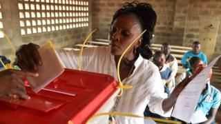 A woman casts her vote at a polling station on December 30, 2015 as people go to the polls to take part in the country's presidential and legislative in the Muslim district in¨PK5 in Bangui