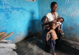 Rebecca breastfeeds one of her two children inside her house