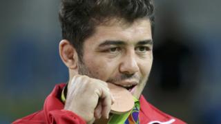 Güreşçi Cenk İldem, kazandığı bronz madalyayı ısırarak poz veriyor.