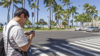 Honolulu'da karşıdan karşıya geçerken mesaj yazan bir adam