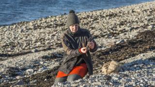 Artist Julia Barton gathering plastic from a beach