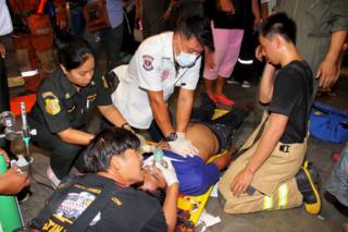 Rescue workers aid a victim after an accident, possibly caused by a fire retardant chemical according to the bank, at the headquarters of Thailand's Siam Commercial Bank in Bangkok 13 March 2016