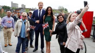 People pose for pictures and selfies with models of Britain"s Prince Harry and Meghan Markle ahead of their wedding, in Windsor