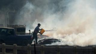Hombre arroja agua al incendio.