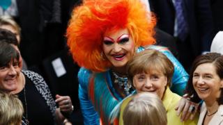Olivia Jones with Chancellor Merkel (C) and national football manager Joachim Low (L)