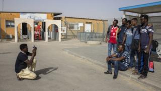 Eritrean migrants pose for a group photograph after being released from the Holot detention facility (rear) near Nitzana in the Negev Desert in Israel, 06 March 2018. The African, from Eritrea and Sudan are among some 100 African immigrants Israel is releasing as they clear the prison ahead of its closure.