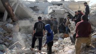 Syrian men and rescue workers search for survivors after air strikes in rebel-held city of Idlib on 7 February 2017