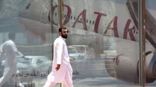 सऊदी अरब में क़तर एयरवेज़ के दफ़्तार के सामने से गुज़रते एक व्यक्ति