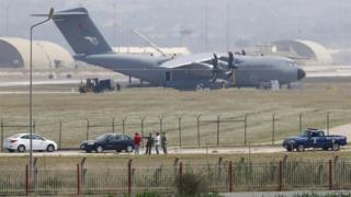 Turkish and US soldiers, with a Turkish Air Force A400M tactical transport aircraft in the background, conduct inspections inside Incirlik airbase