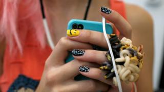 woman with coloured nails holding phone