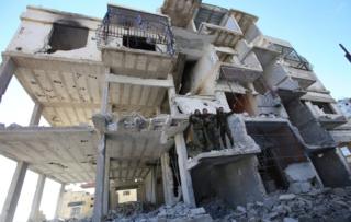 Members of the Syrian pro-government forces pose for a picture in a destroyed building in Salma, in Latakia province in January 2016, following its recapture from rebel fighters
