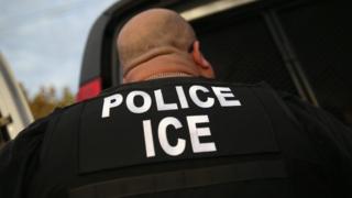 An officer with ICE written on his back