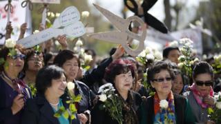 巴黎共和国广场悼念刘少尧集会现场一群妇女举起剪刀形标语牌(2/4/2017)