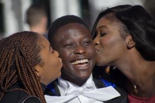 Two women kiss a boy on the cheeks at Cambridge University.