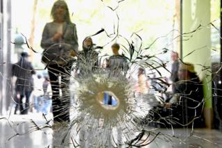 People look at a bullet hole in a window near to the Marks and Spencer on the Champs Elysees in Paris following the shooting of a police officer, 21 April