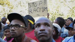 Protesters in South Africa hold up a "stop racism" sign