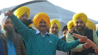 Arvind Kejriwal (C) holds a sword presented by AAP leader Jaswinder Singh and AAP MP Bhagwant Mann during an AAP rally in Majitha, some 25 kms from Amritsar on December 14, 2016