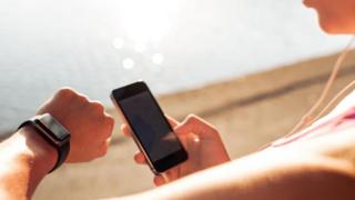 Una mujer chequeando su reloj inteligente y su teléfono celular