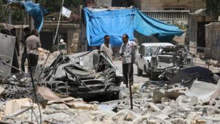 Syrian men inspect damage after air strikes on rebel-held Mashhad district of Aleppo (13 June 2016)