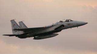 An F-15 jet in the air against a pinkish sky