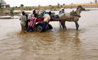 Displaced people carry their belongings to get away from flood during heavy rain at Nyala locality in South Darfur, Sudan 3 June 2017.