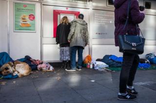 People take cash out next to a homeless person