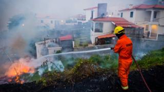 A fireman hoses a fire in a residential area of the city of Funchal, Madeira island, Portugal, 10 August 2016