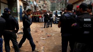 Police officers and criminal investigators look for evidence in front of a bakery, after it was looted in Caracas