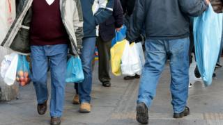 Consumers carry plastic bags on a street of central Athens
