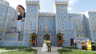 Lego figures of Britain's Prince Harry and Meghan Markle pose in front of a model of Windsor Castle
